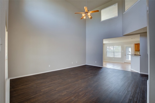 unfurnished living room featuring a towering ceiling, ceiling fan, and hardwood / wood-style flooring