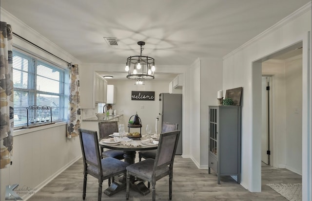 dining room featuring a notable chandelier, hardwood / wood-style floors, and crown molding