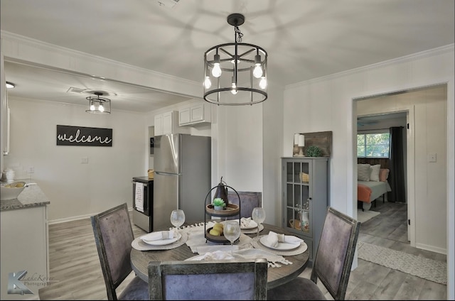 dining area featuring crown molding, light hardwood / wood-style floors, and a chandelier