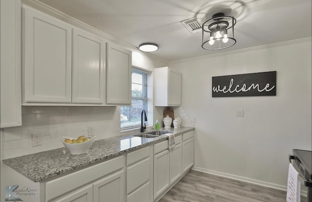 kitchen with white cabinets, sink, crown molding, and light hardwood / wood-style floors