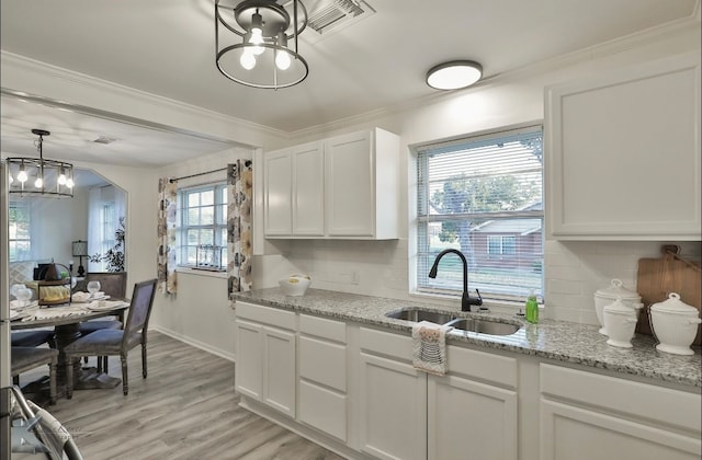 kitchen with backsplash, white cabinetry, sink, and light hardwood / wood-style flooring