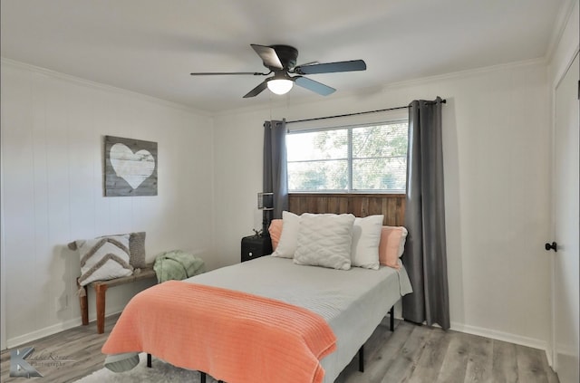 bedroom with ceiling fan, wooden walls, light hardwood / wood-style flooring, and ornamental molding