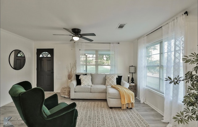 living room with light wood-type flooring, ceiling fan, and crown molding