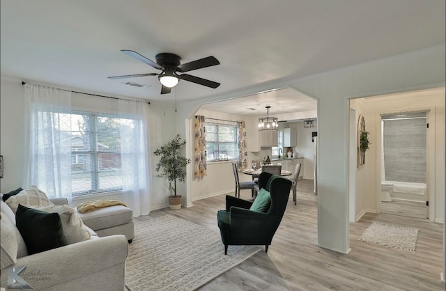 living room with ceiling fan with notable chandelier and light hardwood / wood-style floors