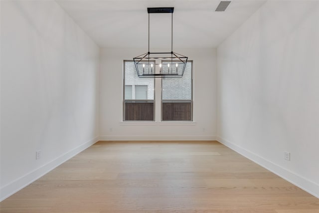 unfurnished dining area with light hardwood / wood-style floors and an inviting chandelier