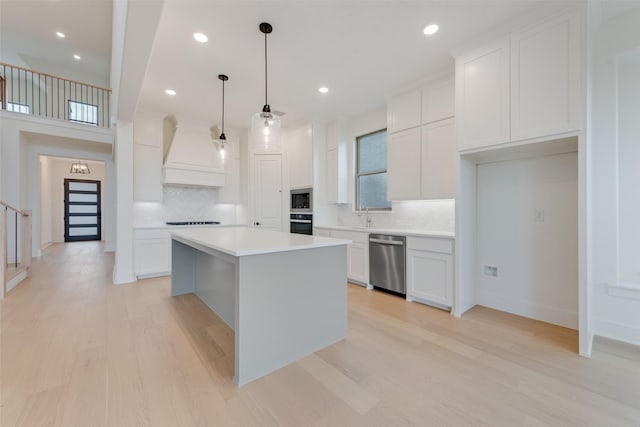 kitchen featuring white cabinetry, a center island, light hardwood / wood-style floors, and custom range hood