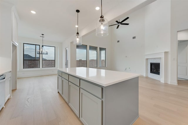 kitchen featuring ceiling fan with notable chandelier, pendant lighting, light hardwood / wood-style flooring, a center island, and gray cabinets