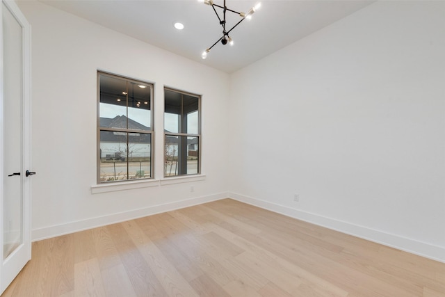 empty room featuring a chandelier and light hardwood / wood-style floors