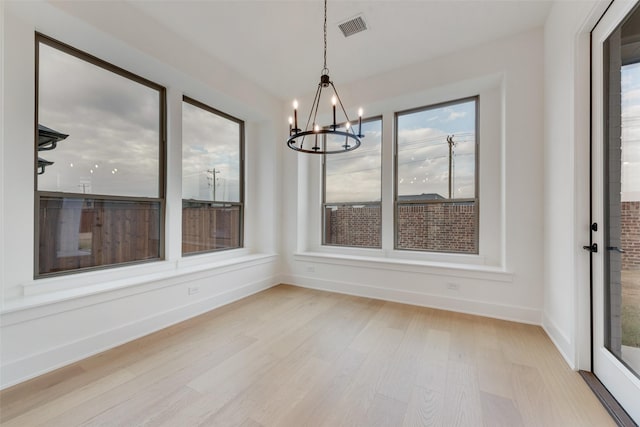 unfurnished dining area featuring a chandelier and light wood-type flooring