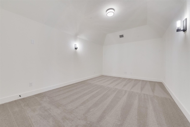 carpeted empty room featuring vaulted ceiling