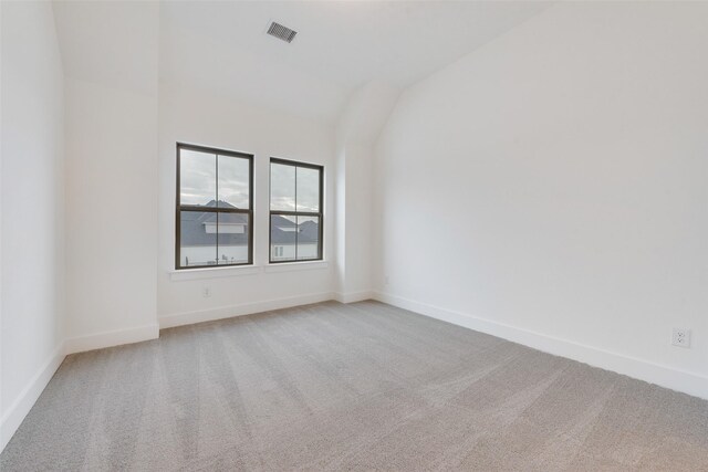 carpeted spare room featuring lofted ceiling