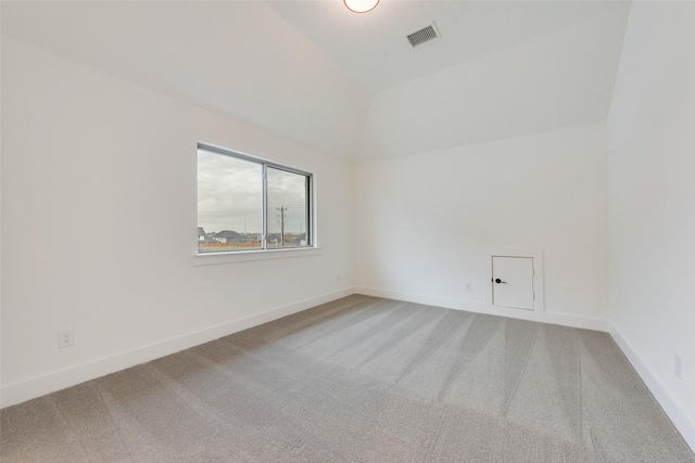 empty room featuring carpet flooring and vaulted ceiling