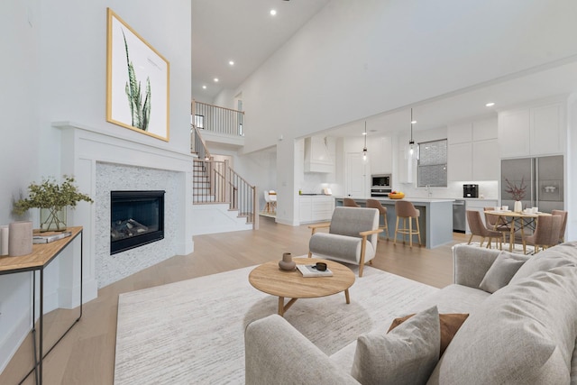 living room with a tile fireplace, sink, high vaulted ceiling, and light hardwood / wood-style flooring