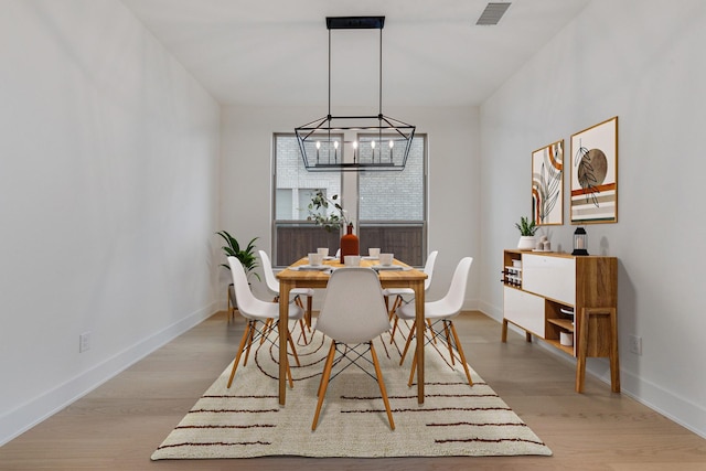 dining room with light wood-type flooring and an inviting chandelier