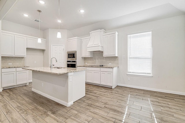 kitchen with white cabinets, pendant lighting, custom range hood, and appliances with stainless steel finishes