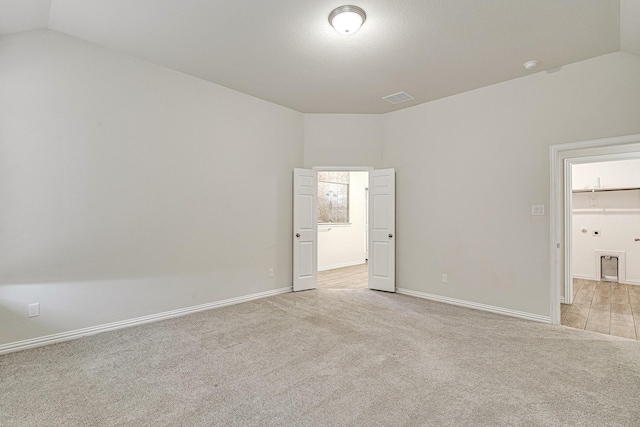 unfurnished bedroom featuring light colored carpet and lofted ceiling