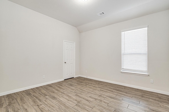 unfurnished room with vaulted ceiling and light hardwood / wood-style flooring