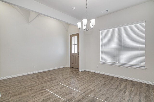 unfurnished room featuring wood-type flooring and a notable chandelier