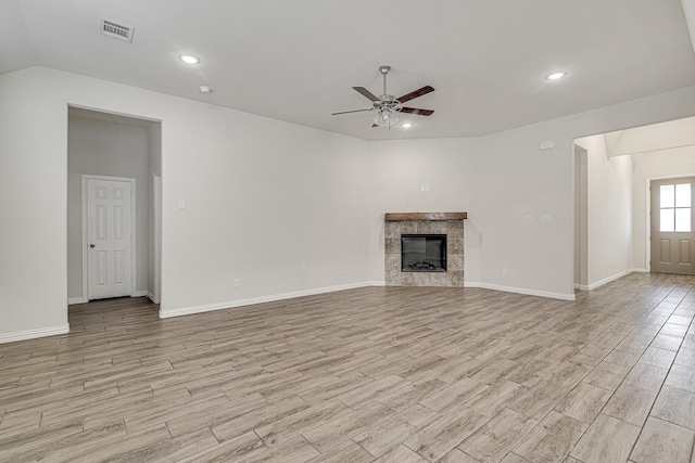 unfurnished living room with ceiling fan and a tiled fireplace