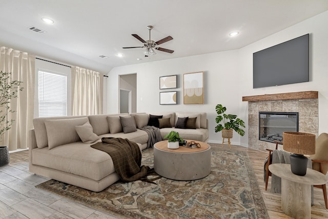 living room featuring a tiled fireplace and ceiling fan