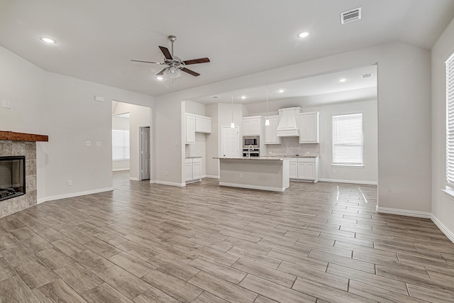 unfurnished living room with ceiling fan and a fireplace