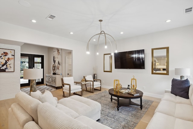 living room with an inviting chandelier and light hardwood / wood-style floors