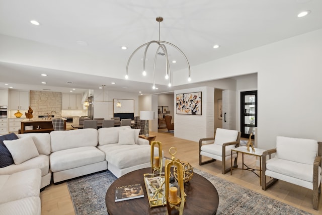 living room with light wood-type flooring, an inviting chandelier, and sink