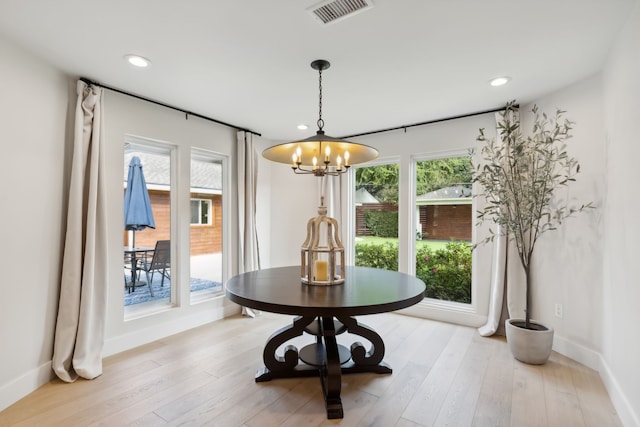 dining area with a notable chandelier, light wood-type flooring, and plenty of natural light