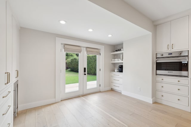 kitchen featuring light hardwood / wood-style flooring, stainless steel oven, and white cabinetry