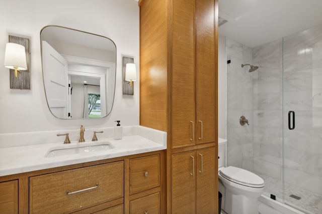 bathroom featuring a shower with shower door, vanity, and toilet