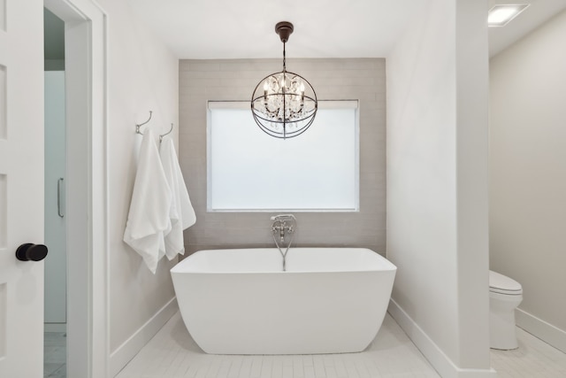 bathroom with an inviting chandelier, tile patterned flooring, a bath, and toilet