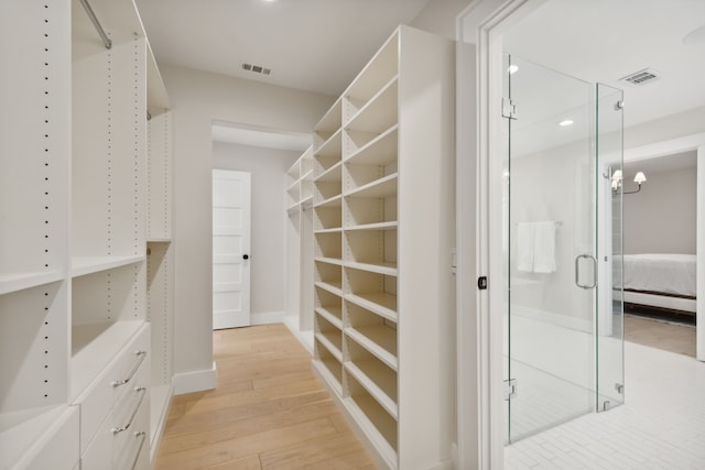 spacious closet featuring a notable chandelier and light hardwood / wood-style floors