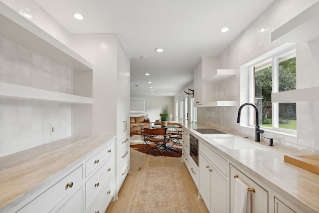 kitchen with light hardwood / wood-style flooring, plenty of natural light, sink, and white cabinetry