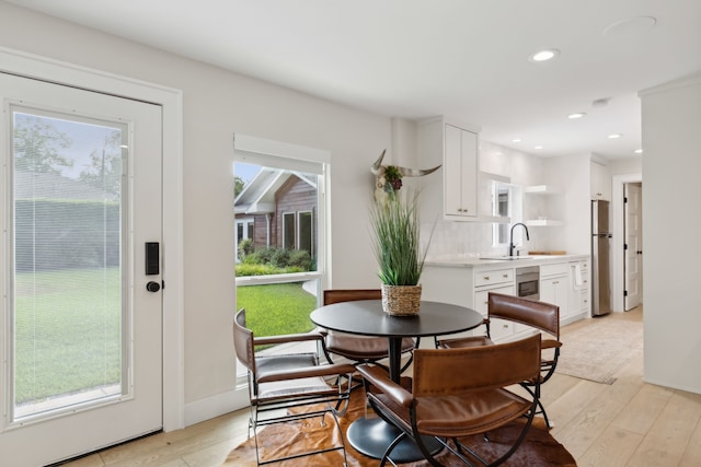 dining area featuring light wood-type flooring, a healthy amount of sunlight, and sink