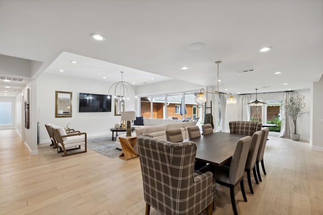 dining space with light wood-type flooring and a notable chandelier