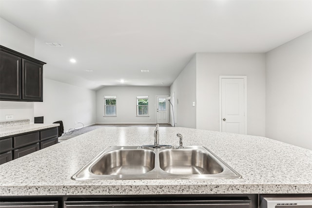 kitchen with lofted ceiling, a center island with sink, and sink