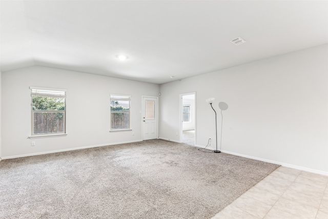 spare room featuring vaulted ceiling and light carpet