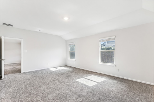 carpeted empty room featuring vaulted ceiling