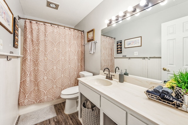 bathroom with wood-type flooring, a shower with curtain, vanity, and toilet