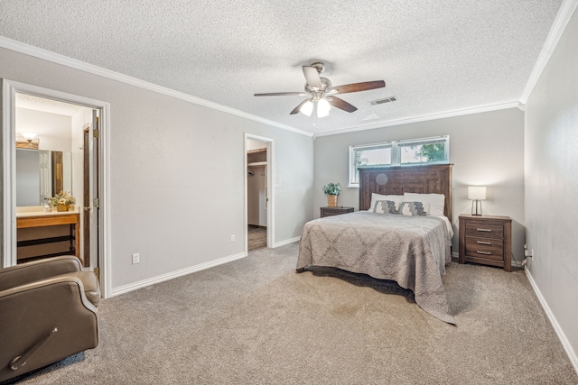 carpeted bedroom with a textured ceiling, ornamental molding, ensuite bath, and ceiling fan