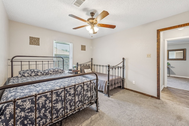 carpeted bedroom with ceiling fan and a textured ceiling