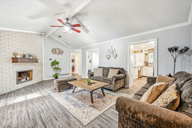 living room featuring light wood-type flooring, a textured ceiling, a fireplace, and ceiling fan