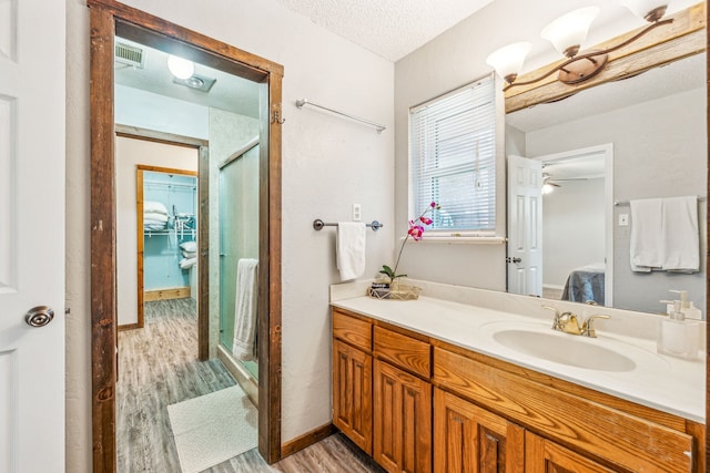 bathroom featuring vanity, a textured ceiling, walk in shower, and hardwood / wood-style floors