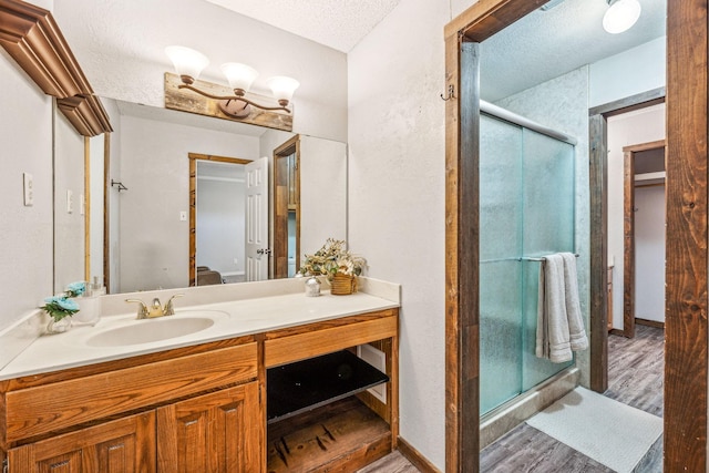 1424 Prairie Wind Blvd, Stephenville, TX 76401 - bathroom with wood finished floors, vanity, a shower stall, and a textured ceiling