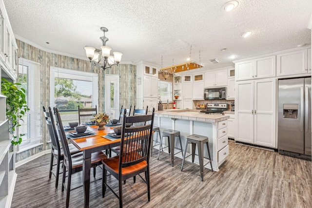 1424 Prairie Wind Blvd, Stephenville, TX 76401 - dining room featuring a textured ceiling, wood finished floors, ornamental molding, a chandelier, and baseboards