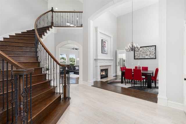 entrance foyer with ceiling fan with notable chandelier, a towering ceiling, and wood-type flooring