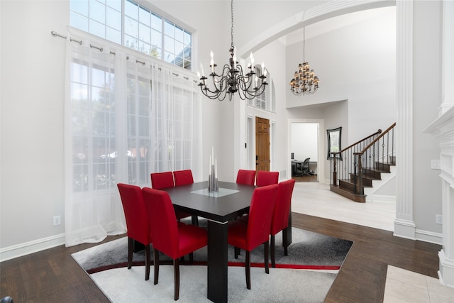 dining area featuring an inviting chandelier, a towering ceiling, and hardwood / wood-style floors