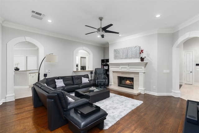 living room featuring a tile fireplace, ornamental molding, dark hardwood / wood-style floors, and ceiling fan