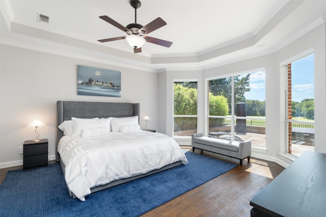 bedroom with a tray ceiling, ceiling fan, dark hardwood / wood-style floors, and crown molding