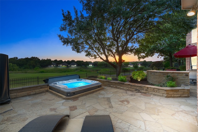 patio terrace at dusk featuring an outdoor hot tub